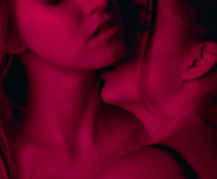 Two women kissing under a red light