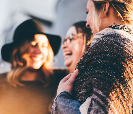 A group of women laughing outdoors during golden hour