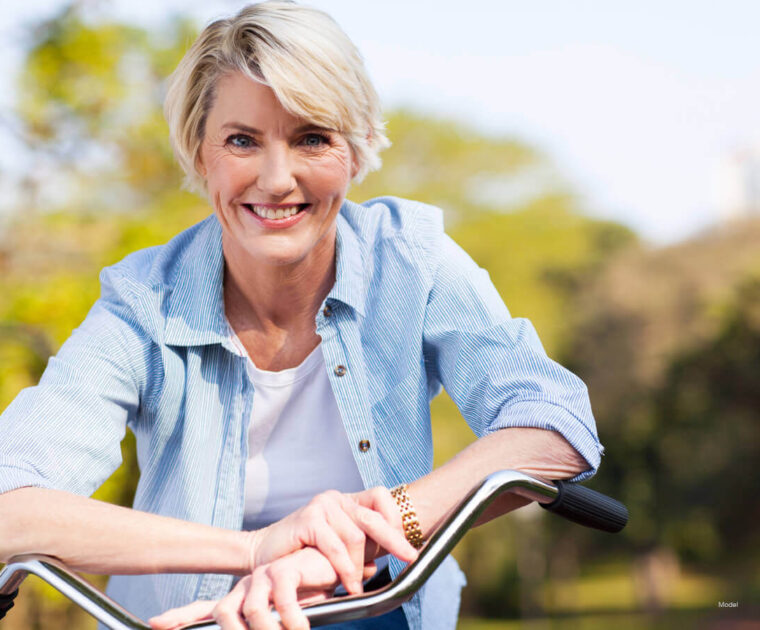 Middle-aged woman sitting on a bike outdoors.