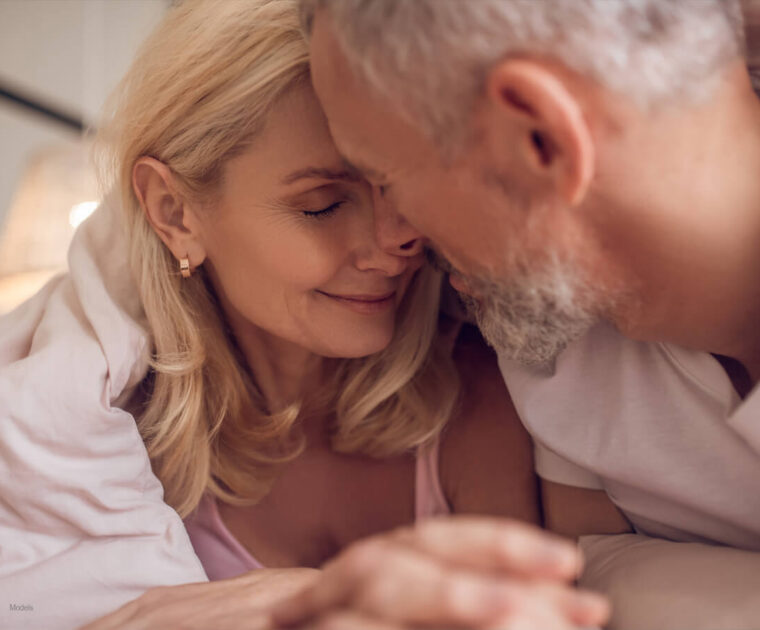 Middle-aged couple snuggling in bed.
