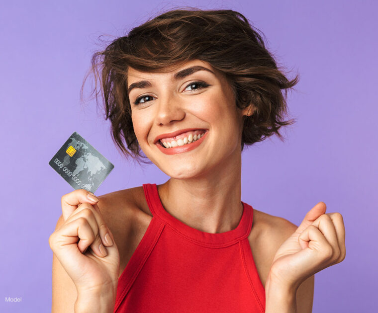 Woman in red holding a credit card